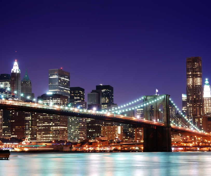 New York City Brooklyn Bridge et Manhattan skyline avec des gratte-ciel sur la rivière Hudson illuminé avec des lumières au crépuscule après le coucher du soleil.